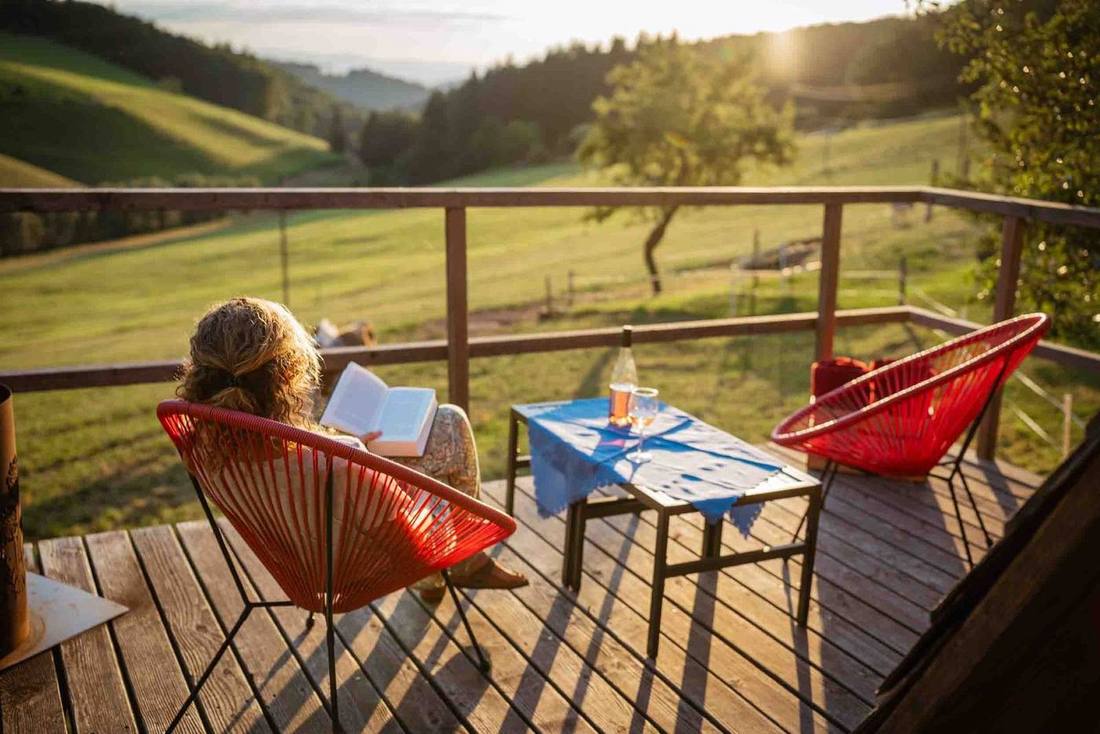 Frau liest auf der Terrasse des Häusle bei der Linde mit Blick ins Grüne